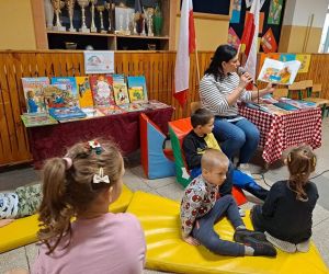 Nauczycielka czyta książkę i pokazuje dzieciom ilustracje