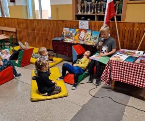 Chłopiec czyta książkę, dzieci siedzą na na piankach