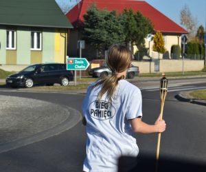 Ulica. Jedna osoba biegnie z pochodnią