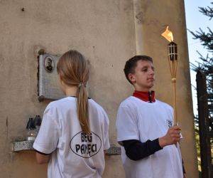 Dwie osoby stoi przy tablicy umieszczonej na budynku