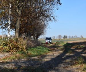 Droga. W głębi jedna osoba biegnie z pochodnią. Za nią samochód