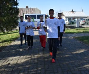 Chodnik na cmentarzu. Pięć osób idzie ze zniczami