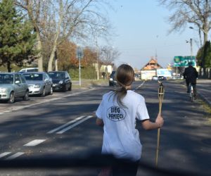 Ulica. Jedna osoba biegnie z pochodnią
