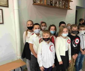 Uczniowie klasy IIII w strojach galowych i maskach, z przypiętymi kotylionami w barwach narodowych.