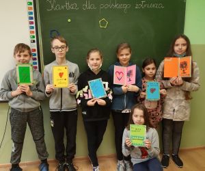 Uczniowie klasy czwartej trzymają w rękach wykonane przez siebie kartki dla obrońców granic