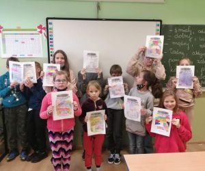 Uczniowie trzymają w rękach wykonane prace plastyczne na temat swoich pozytywnych cech charakteru