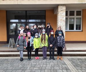 Grupa uczniów z opiekunem stoją przed kinem Plon