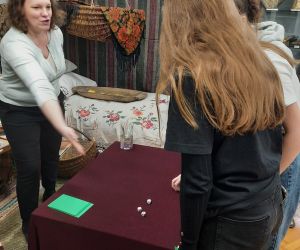 Dwie uczennice rzucają kostkami do gry podczas wróżb w muzeum