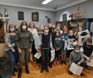 Uczniowie i prowadząca warsztaty andrzejkowe pozują do zdjęcia w jednej z muzealnych sal