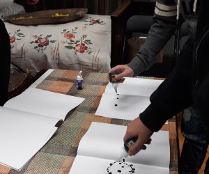 Uczniowie robią kleksy na kartkach papieru