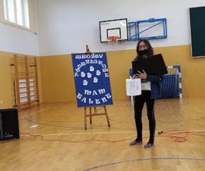 Uczennica pokazuje prace plastyczne przedstawiające postacie