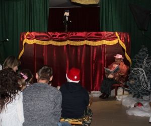 Kukiełki w przedstawieniu teatrzyku kukiełkowym. Narrator siedzi przed parawanem.