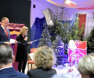 Dwie osoby przemawiają do mikrofonu wewnątrz budynku.