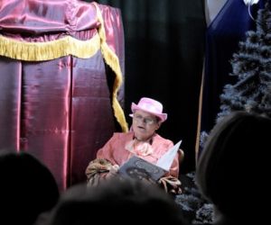 Narrator czyta książkę podczas przedstawienia teatralnego.