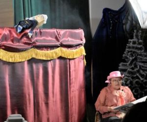 Kukiełki w przedstawieniu teatrzyku kukiełkowym. Narrator siedzi przed parawanem.