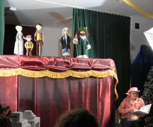 Kukiełki w przedstawieniu teatrzyku kukiełkowym. Narrator przed parawanem.