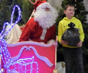 Dziecko odbiera paczkę od Mikołaja.