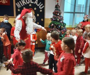 Uczniowie i przedszkolaki tańczą w kółku z Mikołajem