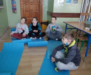 Uczniowie siedzą na matach i słuchają baśni