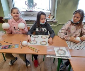 Uczennice siedzą przy stoliku i szykują materiały do wykonania bombki