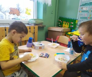 chłopcy jedzą sałatkę owocową