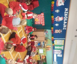 Ubrane w czerwone stroje dzieci czekają na Mikołaja