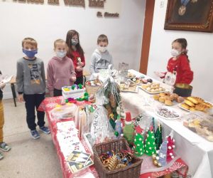 Uczniowie zgromadzeni wokół stołu z ciastami i dekoracjami świątecznymi
