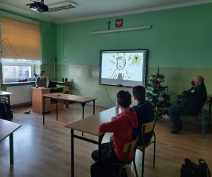 Prowadząca spotkanie prezentuje treści na tablicy multimedialnej