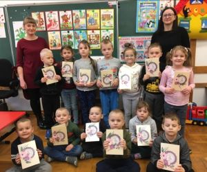 Dzieci stoją w grupie z 2 osobami dorosłymi i prezentują laurki wykonane podczas warsztatów.