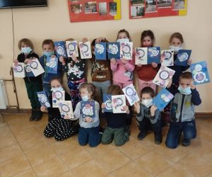 Dzieci stoją w grupie, prezentują laurki wykonane podczas warsztatów.