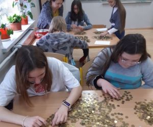 Wolontariusze wraz z opiekunem segregują monety
