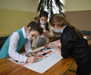 Dzieci siedzą wewnątrz budynku i rozwiązują zadania konkursowe.