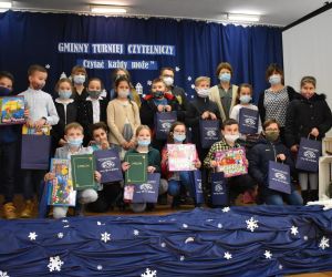 Grupa osób stoi na scenie.