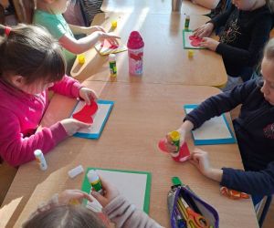 dzieci przy stolikach przygotowują upominki dla dziadków