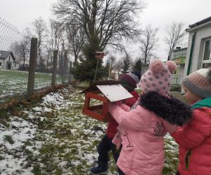 dzieci wsypują ziarna do karmnika