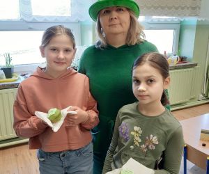 Nauczycielka w irlandzkim kapeluszu z uczennicami, które trzymają zielone mufinki