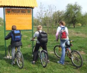 troje dzieci z rowerami, patrzą na tablicę informacyjną