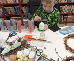 Osoby wykonują ozdoby wielkanocne podczas warsztatów