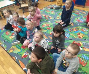 Dzieci słuchają i siedzą na dywanie