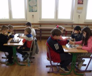 Uczniowie klas młodszych rozgrywają mecze warcabowe przy stolikach