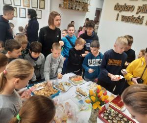 Uczniowie kupują ciasta przy stole