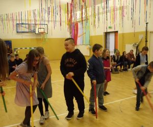 Czwartoklasiści w sali gimnastycznej, trzymają w dłoniach kije hokejowe