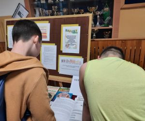 Uczniowie czytają książki prezentowane na wystawie na szkolnym korytarzu