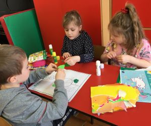 Dzieci w grupie wyklejają plakat.