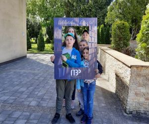 Dziewczynki i chłopcy robią sobie wspólne zdjęcie używając ramki z logo biblioteki. 