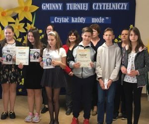 Chłopcy i dziewczęta - uczestnicy turnieju czytelniczego na tle tablicy dekoracyjnej