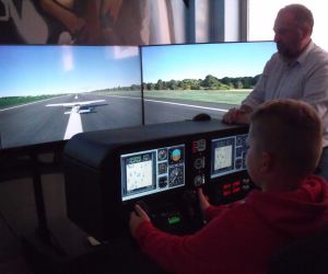 Uczeń wraz z pracownikiem Muzeum Strefa Historii w Świdniku przed sterami symulatora lotu 