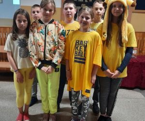 Uczniowie w żółtych ubraniach stoją na szkolnym korytarzu