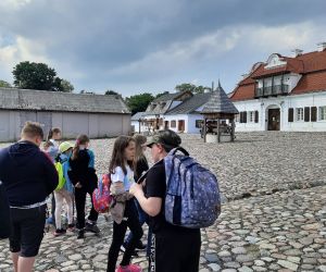 Uczniowie stoją na rynku prowincjonalnego miasteczka w skansenie