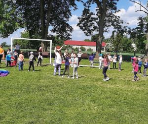 Dzieci z animatorką bawią się w kółku na boisku szkolnym